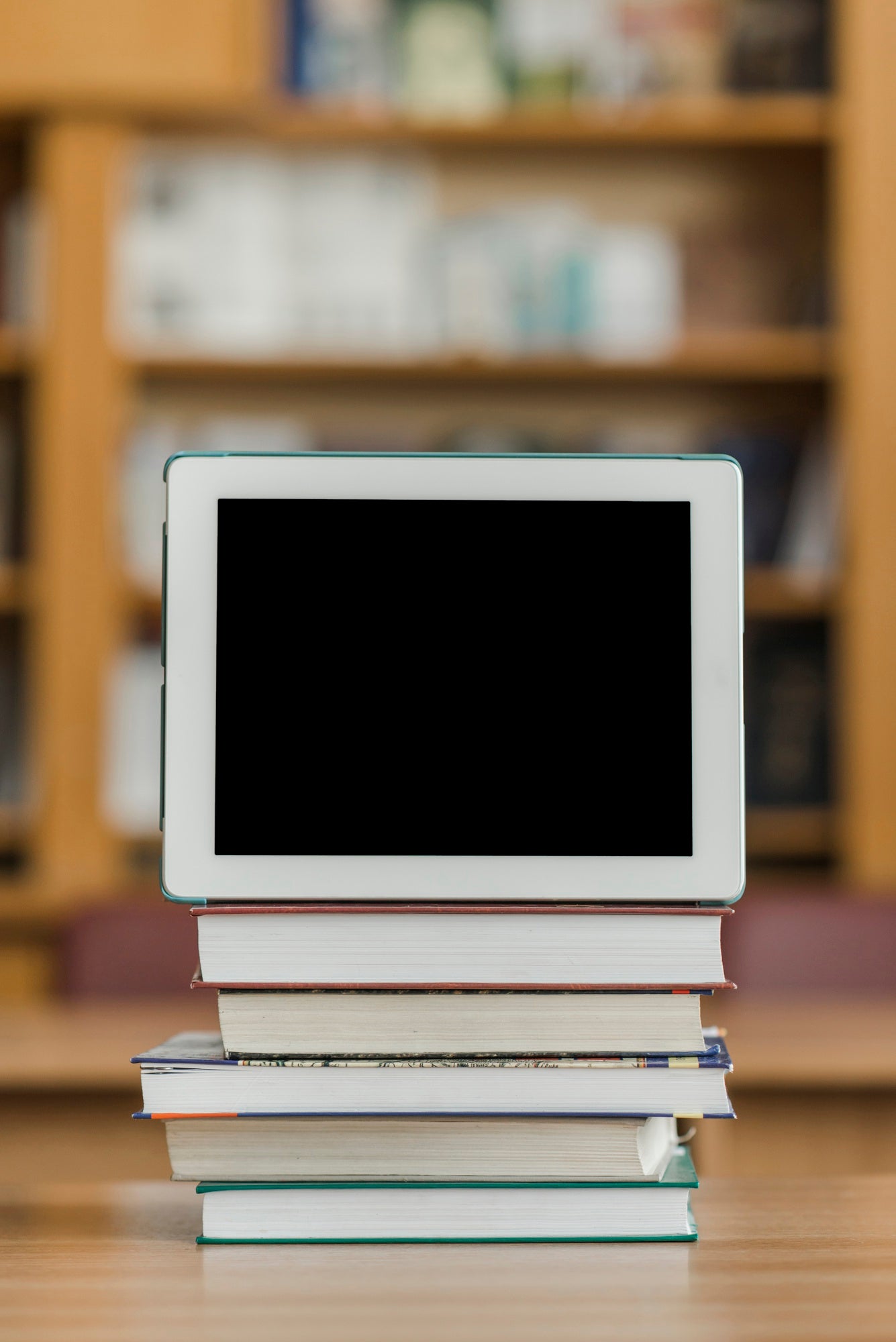 ebook prodict category featuring a digital tablet on a stack on books in a library setting with a blurred background